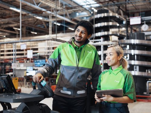 To Bring-kolleger står smilende ved siden af hinanden på et lager