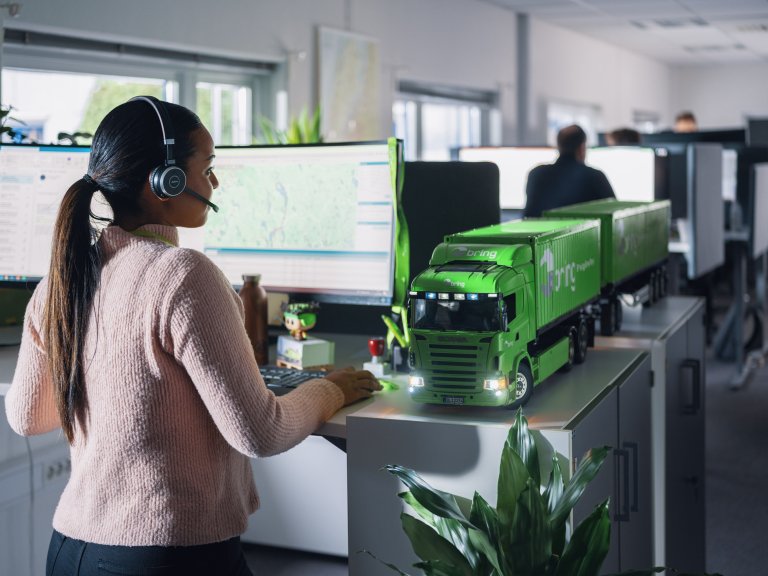 En kvindelig medarbejder hos Bring kundeservice har et headset på foran en computerskærm