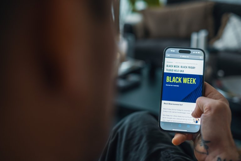 En person sidder med en mobil i hånden med en netbutik, der viser, at det er Black Week