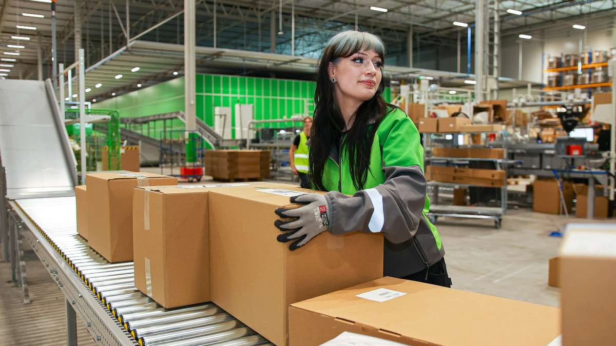 En medarbejder hos Bring står ved et pakkebånd i et Shelfless lager